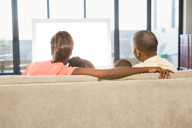 Rear view of family watching TV together with transparent screen - Download Free Stock Videos Pikwizard.com