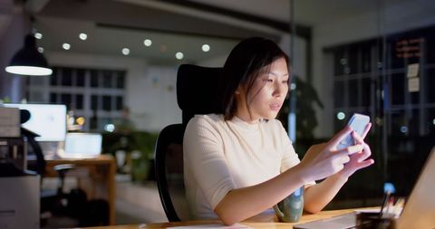 Asian Businesswoman Using Smartphone in Office at Night