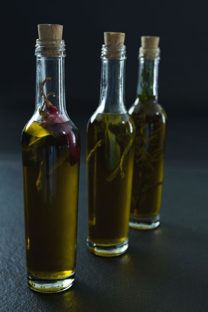Bottles of olive oil with herbs on black background