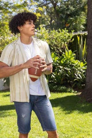 Young Man Holding Football Outdoor in Bright Summer Day
