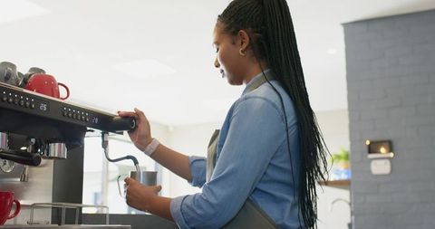 African American Barista Steaming Milk at Commercial Espresso Machine in Modern Bright Cafe