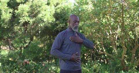 Senior african american man practicing mindful breathing and meditation in sunlit garden