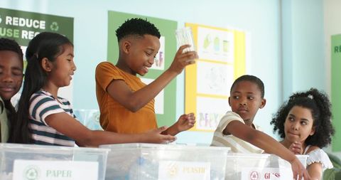 African american students sorting recyclables in school recycling bin learning teamwork
