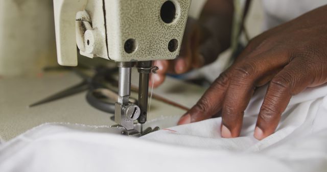 Hands of african american male tailor using sewing machine in workshop. Tailor, small business, work, labor and workshop, unaltered.