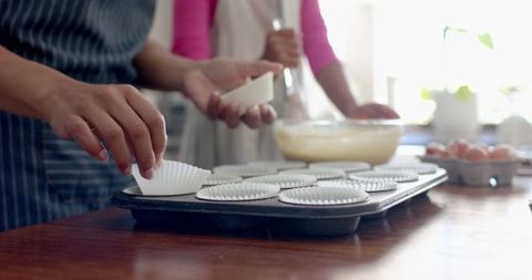 Hands Preparing Cupcake Liners in Modern Home Kitchen
