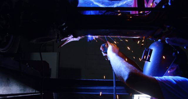 Welder at work in an industrial setting, with copy space. Intense blue light and sparks capture the precision of metal fabrication.