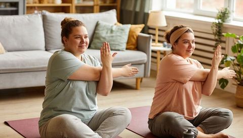 Plus-size women practicing seated twist yoga at home for body-positive wellness