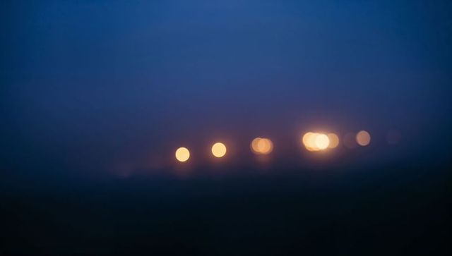 Glowing warm soft bokeh lights stretching across moody twilight horizon with deep blue gradient