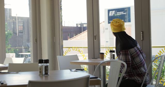 Person in Yellow Headscarf Enjoying Coffee by Window in Cafeteria - Download Free Stock Images Pikwizard.com