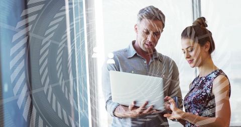 Colleagues Analyzing Data on Laptop with High-Tech Interface