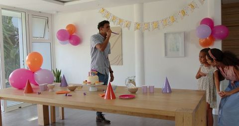 Man preparing indoor birthday party with cake and decorations