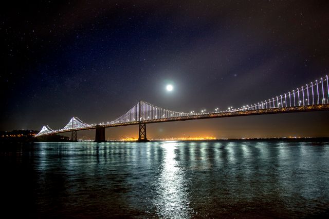 Illuminated City Bridge Under Moonlit Night Sky Over Calm Water - Download Free Stock Photos Pikwizard.com