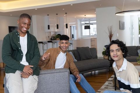 Multicultural friends laughing and chatting in modern open-plan living room