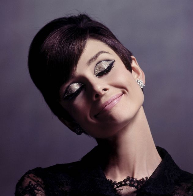 This image features an elegant woman with short hair smiling with her eyes closed. She has cat-eye makeup with glittery eye shadow and is wearing earrings. This classic and stylish look is ideal for beauty and fashion magazines, makeup tutorials, vintage-inspired content, and advertising campaigns focusing on elegance and sophistication.