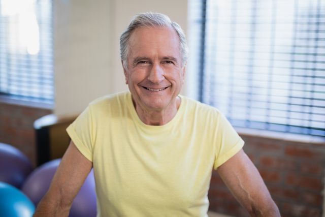 Portrait of smiling senior male patient against window at hospital ward