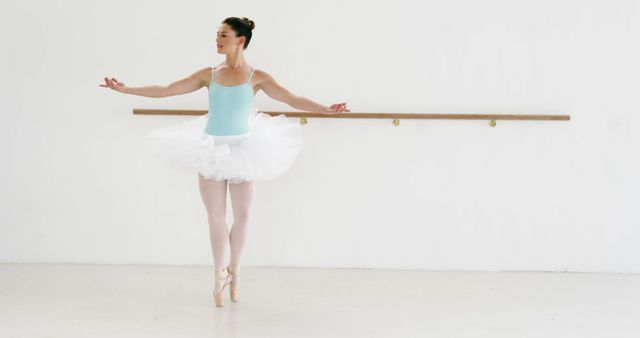 A young Asian ballerina practices her dance routine in a studio, with copy space. Her poise and concentration reflect the discipline of ballet training.