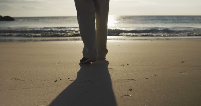 Person Walking on Beach at Sunset with Long Shadow - Download Free Stock Images Pikwizard.com