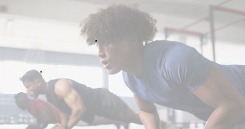 Group performing medicine ball push-ups in gym, team strength training, plank workout
