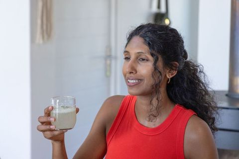 Serene african woman relaxing while holding herbal drink in sunlit cozy minimalist kitchen