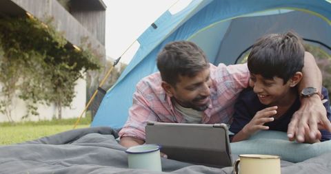 Father and Son Enjoying Backyard Camping with Tablet