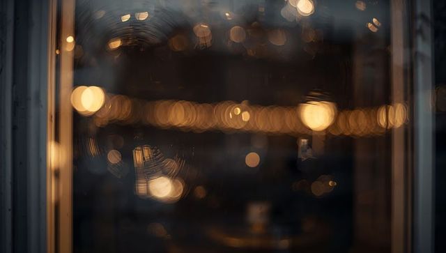 Moody window glass showing amber bokeh, circular smudges and soft reflections