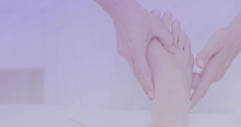 Practitioner cradling foot during soothing foot massage on white linen treatment table