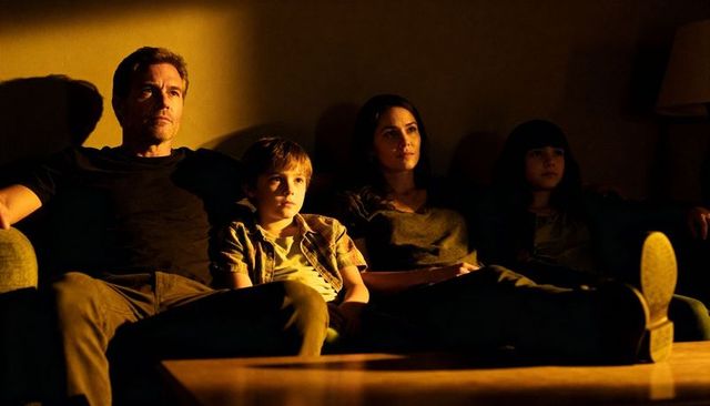 Family relaxing on couch at night warm amber lighting cozy living room movie night moment