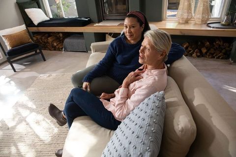 Mature women sharing warm conversation and comforting each other on cozy living room sofa