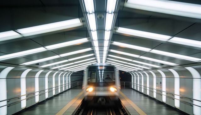 Futuristic metro approaching platform with motion blur and symmetric illuminated tunnel
