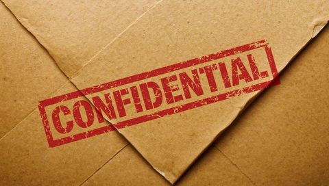 Confidential red stamp on kraft envelope closeup featuring distressed ink on brown paper