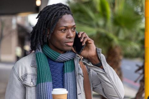 African american man walking and talking on smartphone while holding takeaway coffee cup