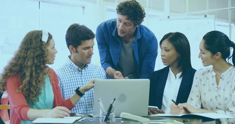 Collaborating five-person team brainstorming around laptop in bright modern office meeting