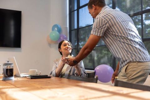 Diverse colleagues sharing cake during office celebration