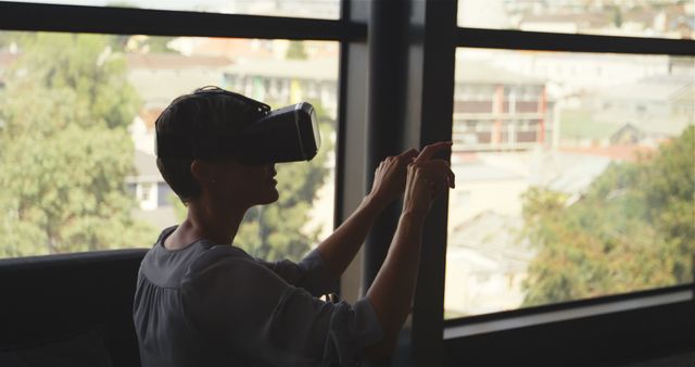 Person Using Virtual Reality Headset in Modern Apartment with Large Windows - Download Free Stock Images Pikwizard.com