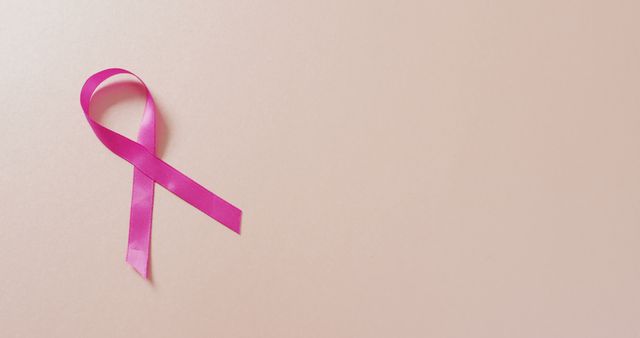 Image of pink breast cancer ribbon on pale pink background. medical awareness support campaign symbol for breast cancer.