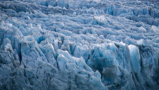 Fractured glacier ice field showing jagged seracs, deep crevasses, and blue ice texture