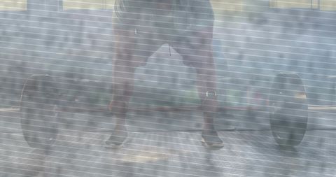 Man performing wide-stance deadlift with heavy loaded barbell in backlit gym haze, low-angle