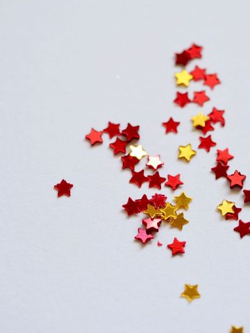 Scattered Red and Gold Star Confetti on White Background