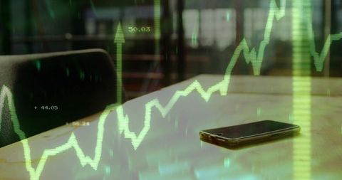 Smartphone on Table with Overlay of Digital Financial Charts