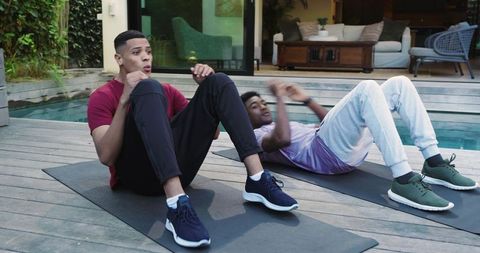 Two Diverse Young Men Exercising on Poolside Deck for Fitness