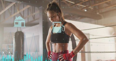 Female boxer catching breath in gym with performance analytics overlay