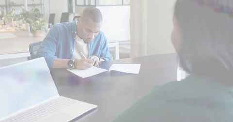 Man writing in notebook during meeting at modern minimalist office table, daylight