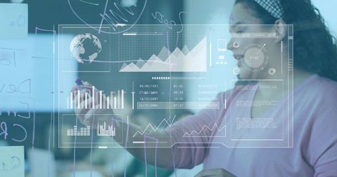 Woman writing on glass with data visualizations and charts in collaborative workspace