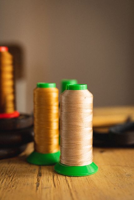 Close-up of thread spools on table against wall with blank space in leather workshop. unaltered, small business, equipment, still life, copy space, handcraft, leather craft and workshop.