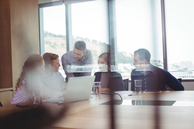 Business people discussing in board room seen through glass at office