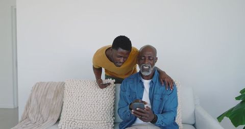 African American Father and Son Relaxing At Home with Smartphones