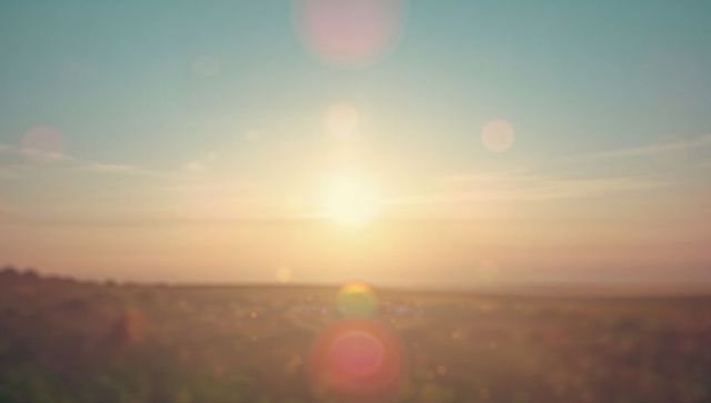 Golden sunrise in tranquil field with natural lens flares