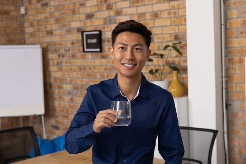 Smiling professional enjoying water in modern workspace