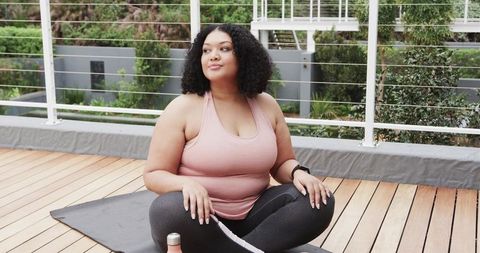 African American woman practicing outdoor mindfulness and home fitness on balcony deck