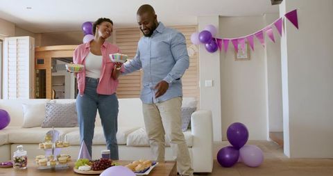 African American couple celebrating at home purple balloons, bunting and dessert table